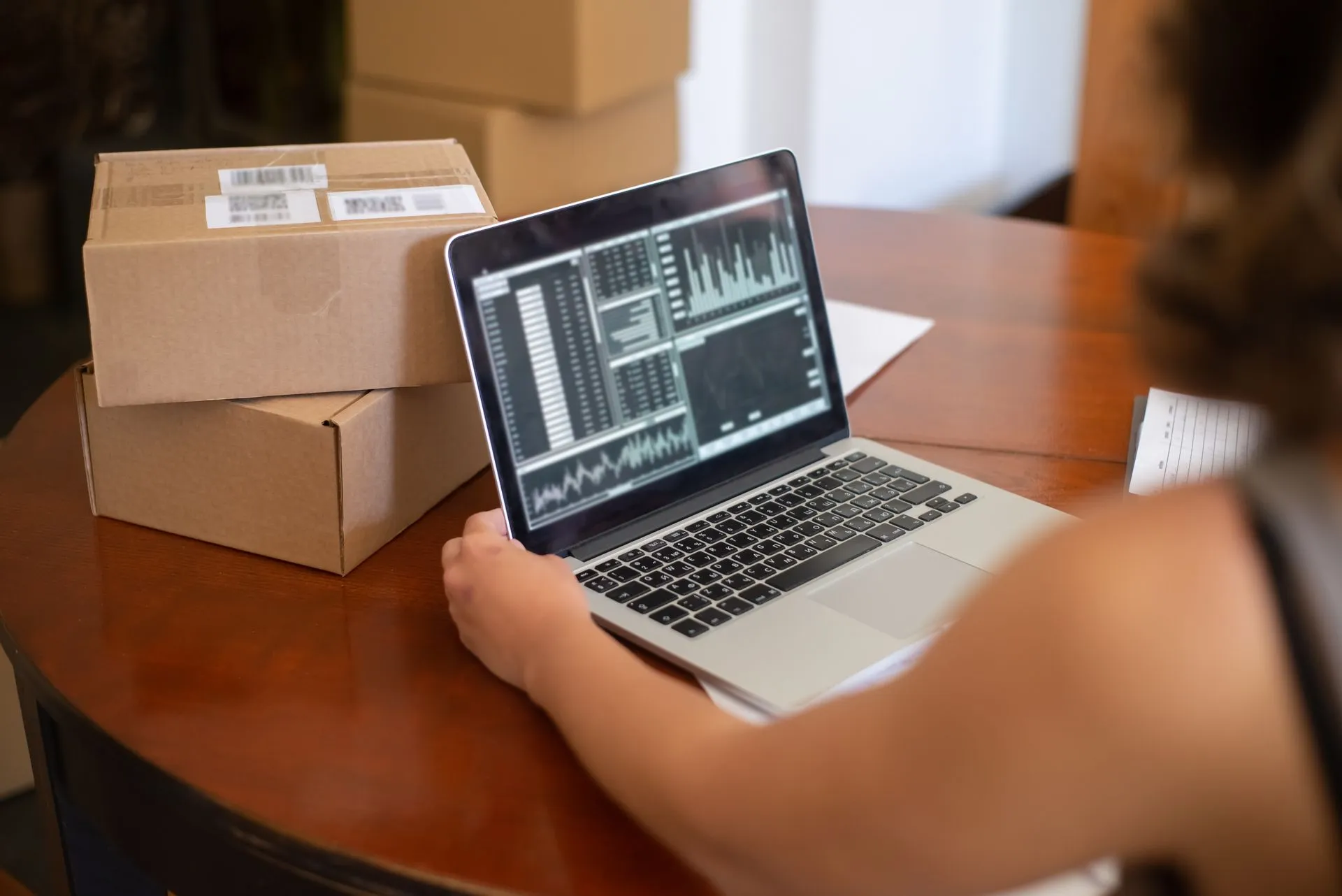 Store owner checking sales charts on a laptop beside two packed parcels